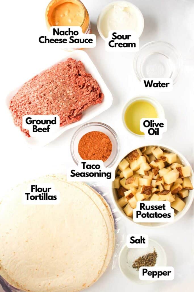 Flat lay of ingredients for a Beef and Potato Burrito Taco Bell Copycat recipe, including ground beef, taco seasoning, russet potatoes, flour tortillas, nacho cheese sauce, sour cream, olive oil, water, salt, and pepper.