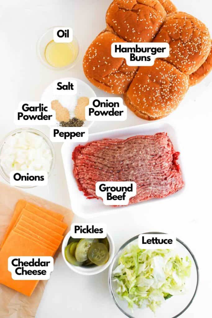 Top-down view of ingredients for hamburgers, including buns, ground beef, cheddar cheese, pickles, lettuce, diced onions&mdash;perfect for making Big Mac Sloppy Joes&mdash;plus oil, salt, pepper, garlic powder, and onion powder.