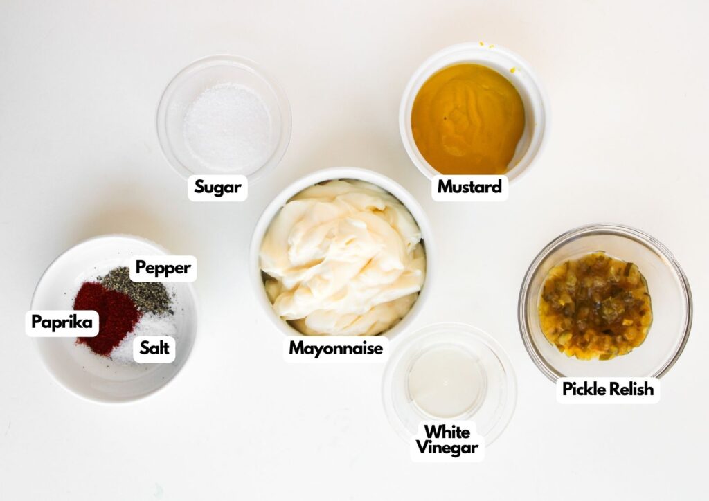 Bowls containing ingredients like mayonnaise, mustard, pickle relish, and more—perfect for making Big Mac Sloppy Joes—arranged on a white surface with each ingredient labeled.