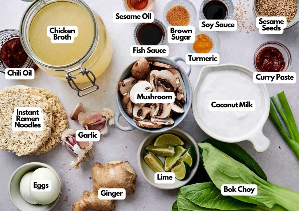A collection of ingredients for Coconut Ramen, including chicken broth, mushrooms, instant noodles, bok choy, coconut milk, lime, eggs, garlic, ginger, sauces, spices, and chili oil.
