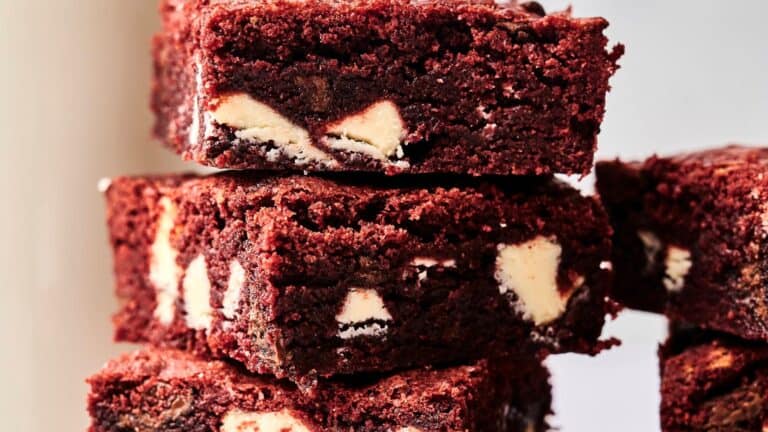 Stack of red velvet brownies with white chocolate chunks.