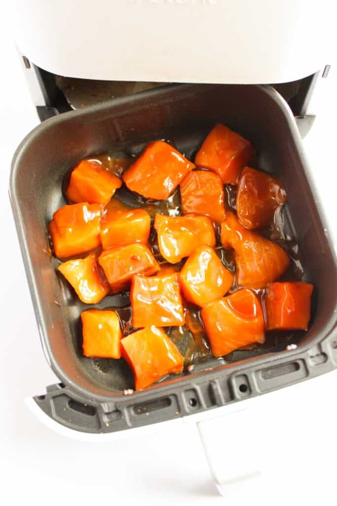 Cubed orange squash pieces, reminiscent of the vibrant hues in a Teriyaki Salmon Bowl, are perfectly glazed and nestled in an air fryer basket.