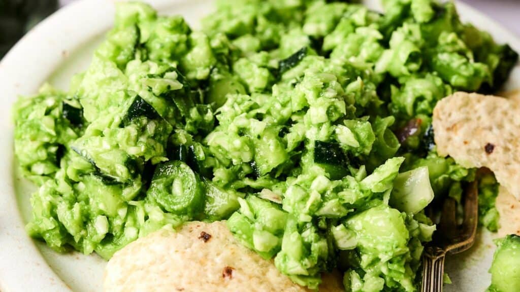 Close-up of a plate with bright green guacamole and tortilla chips.