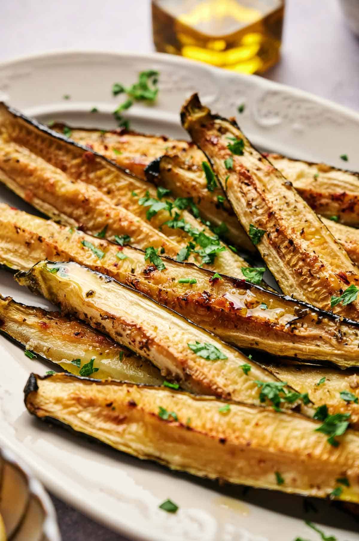 A plate of baked zucchini halves garnished with chopped parsley, served on a white dish.