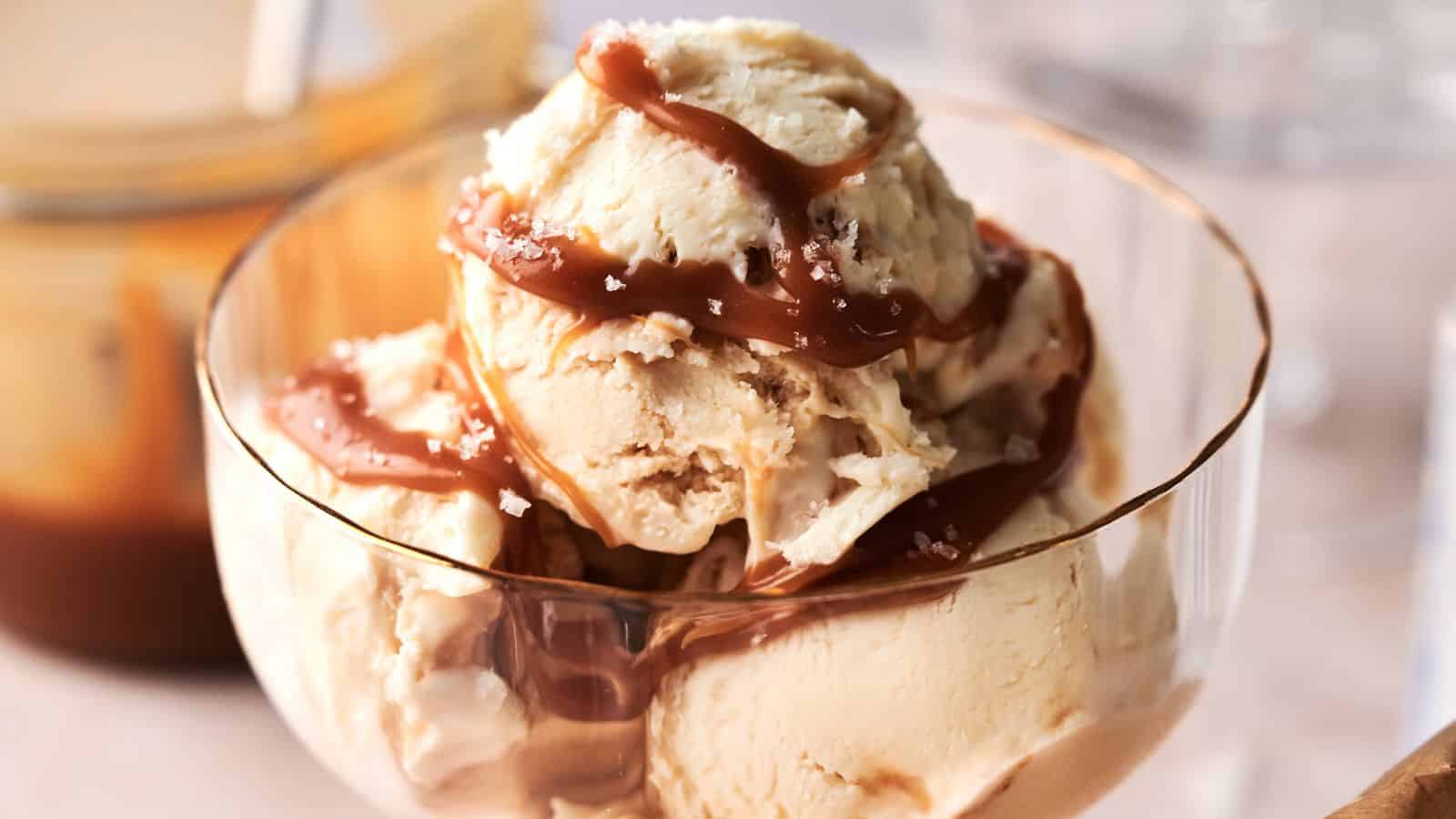 A glass bowl filled with scoops of vanilla ice cream topped with caramel sauce and a sprinkle of sea salt.