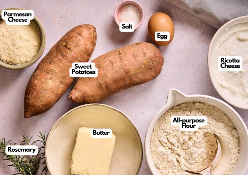 Ingredients for Sweet Potato Gnocchi are laid out on a counter: sweet potatoes, Parmesan cheese, salt, egg, ricotta cheese, all-purpose flour, butter, and rosemary.