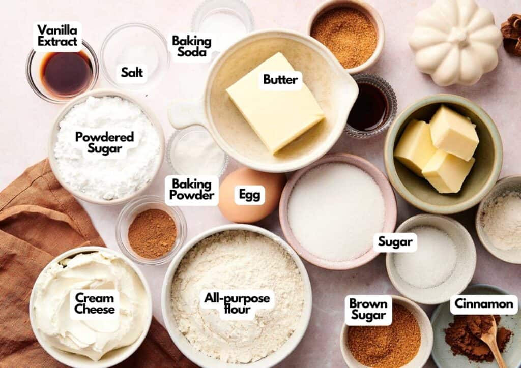 Assorted baking ingredients in bowls and plates, including butter, egg, flour, sugars, cream cheese, spices, vanilla extract, baking powder, baking soda, and salt—everything you need to make Air Fryer Crumbl Cinnamon Swirl Cookies.