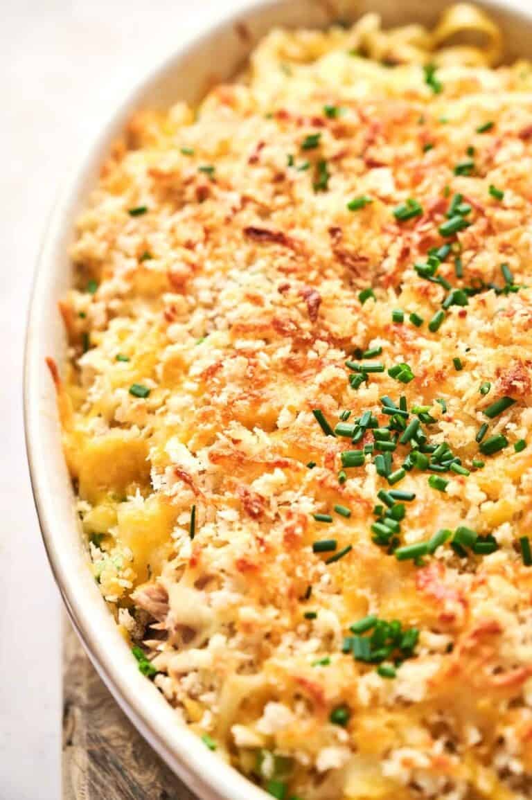 A close-up of a Tuna Casserole topped with golden breadcrumbs and chopped chives in a white oval dish.