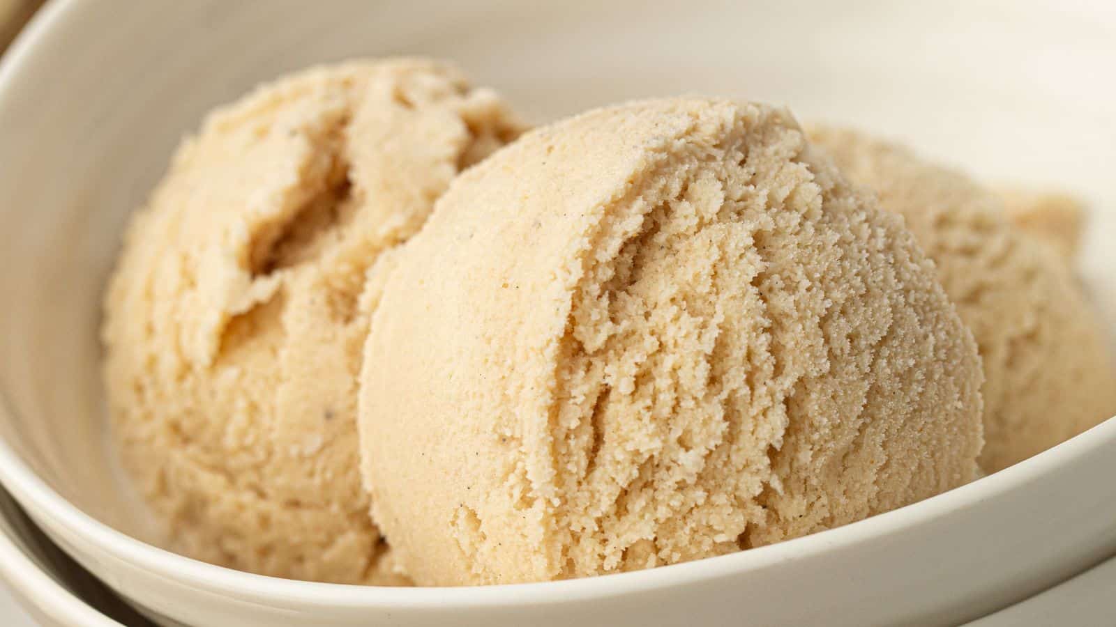 Two scoops of light brown ice cream served in a white bowl.