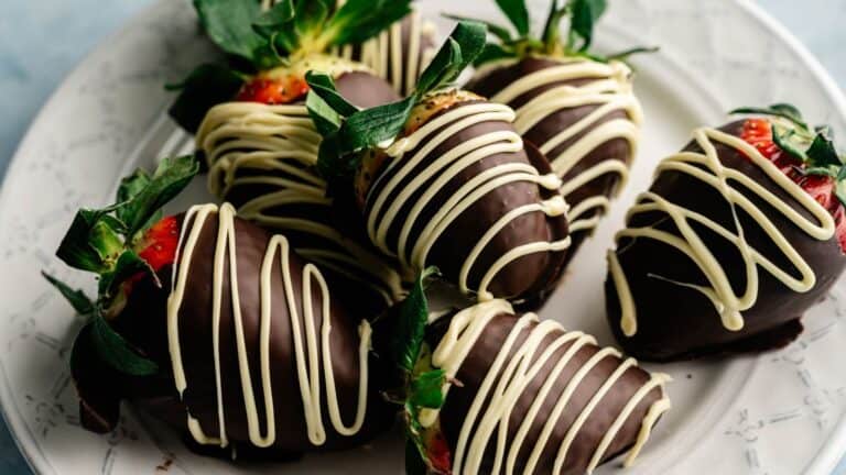 A plate of strawberries dipped in dark chocolate and drizzled with white chocolate.