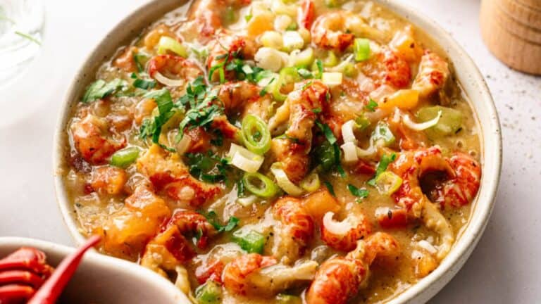 A bowl of soup with shrimp and vegetables.