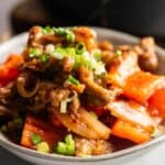 A bowl of stir-fried beef with red bell peppers, onions, and chopped green onions, inspired by Panda Express Beijing Beef.