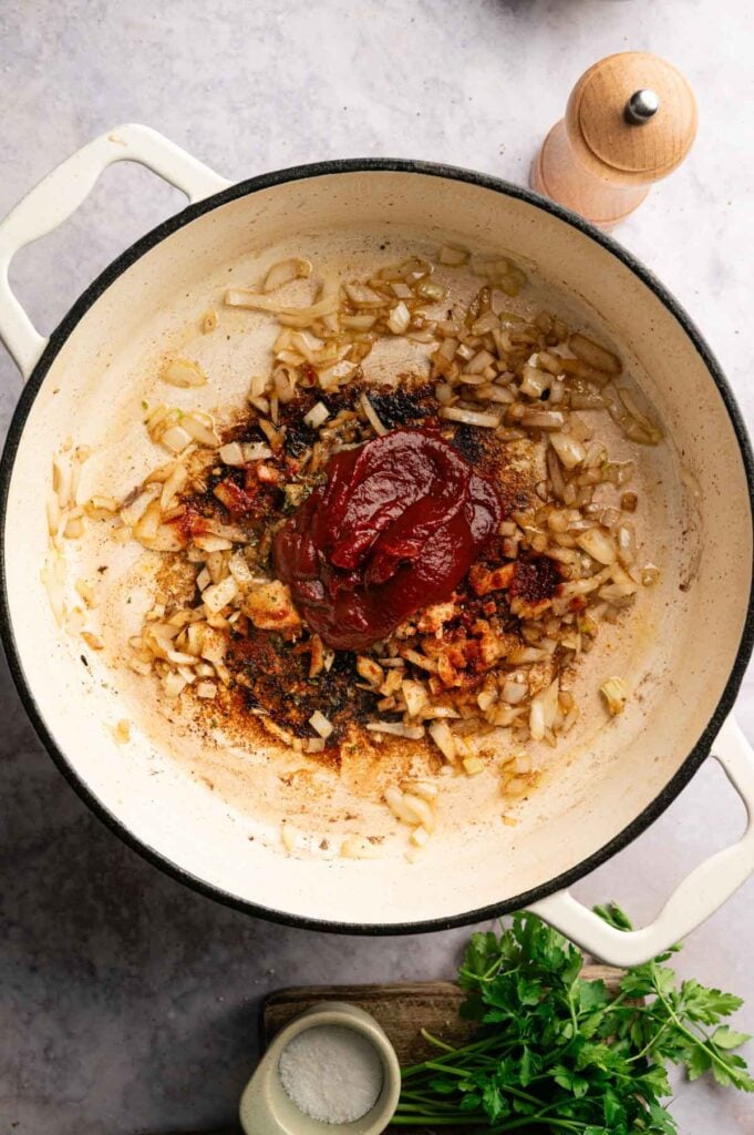 Sautéed onions with tomato paste and paprika added to a Dutch oven.