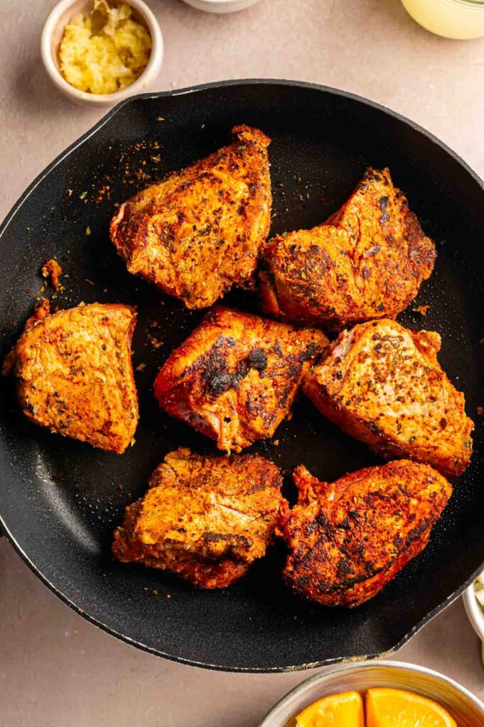 Seasoned pork pieces seared until browned and crusty in a cast iron skillet.