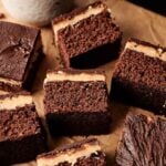 Slices of Air Fryer Buckeye Brownies with a creamy filling are arranged on parchment paper next to a cup of coffee.