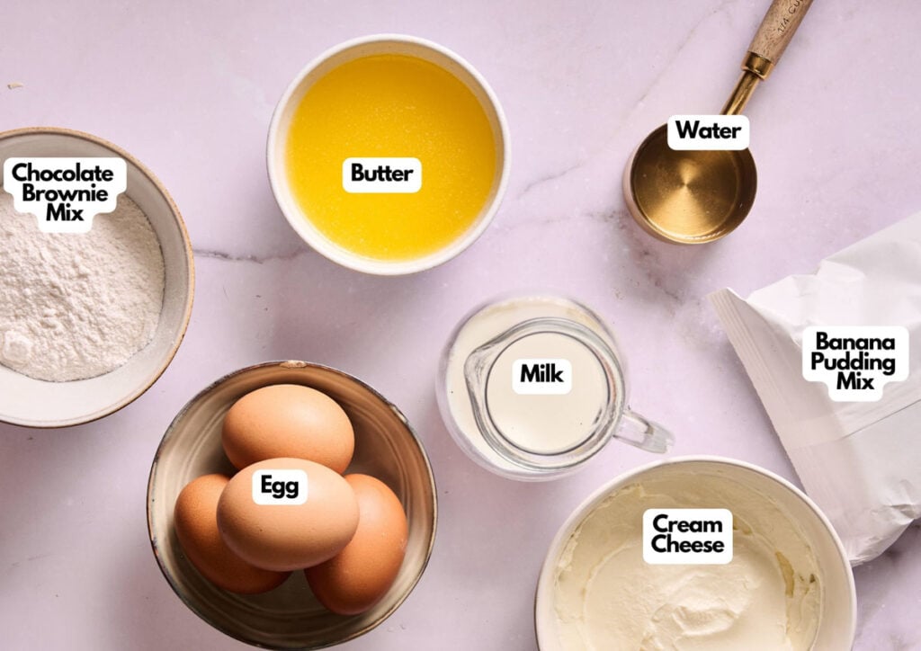 Top view of labeled ingredients in bowls on a countertop for Air Fryer Banana Pudding Brownies: chocolate brownie mix, melted butter, water, egg, milk, banana pudding mix, and cream cheese.
