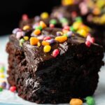A close-up of Air Fryer Cosmic Brownies, featuring a rich chocolate brownie topped with glossy chocolate frosting and colorful candy sprinkles.