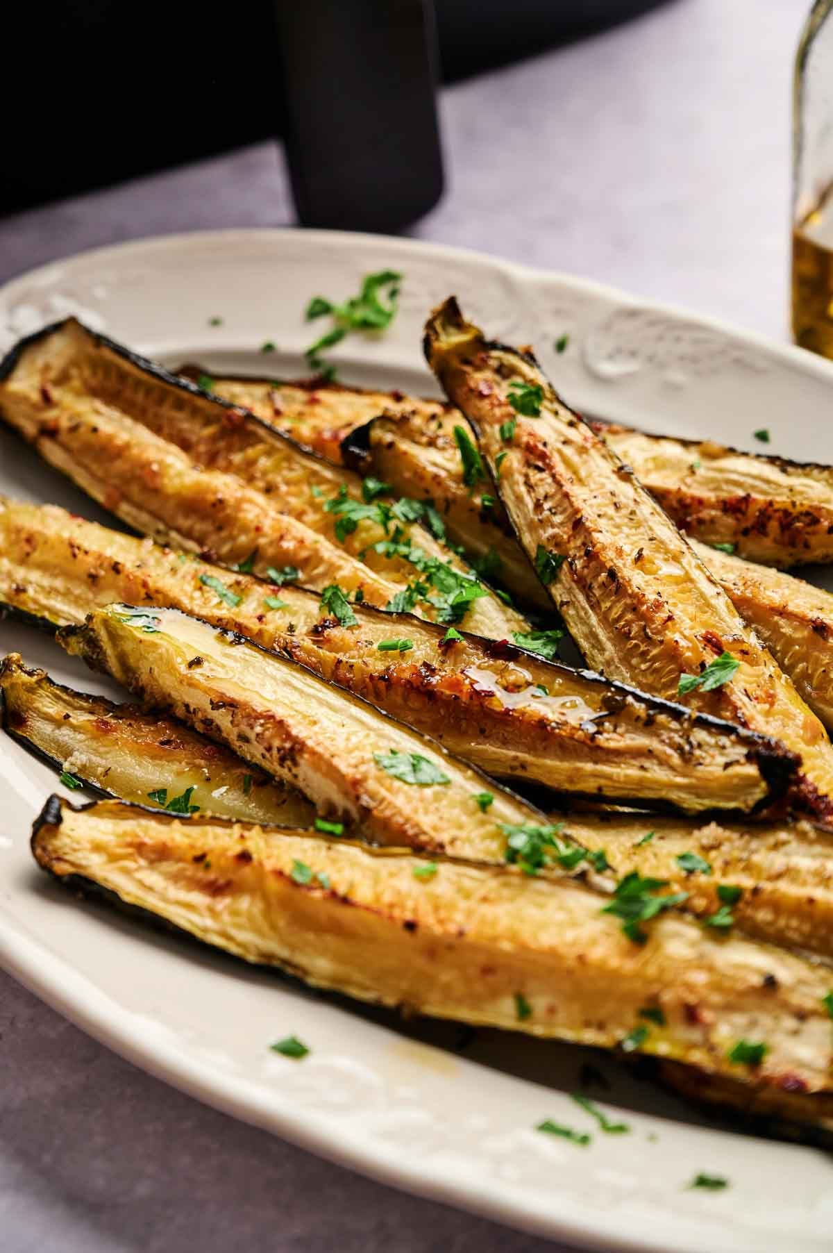 Air Fryer Baked Zucchini halves are garnished with chopped herbs and served on a white dish, creating a delicious and healthy presentation.