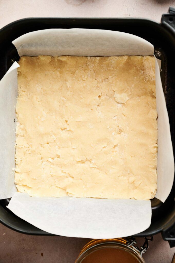Unbaked pecan pie bar crust firmly pressed into a square pan before baking