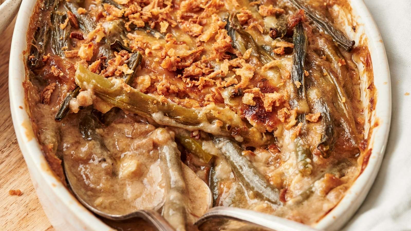 A casserole dish filled with green bean casserole with a spoon in it.